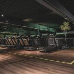 A row of treadmills in a gym with wooden floors and green balloons